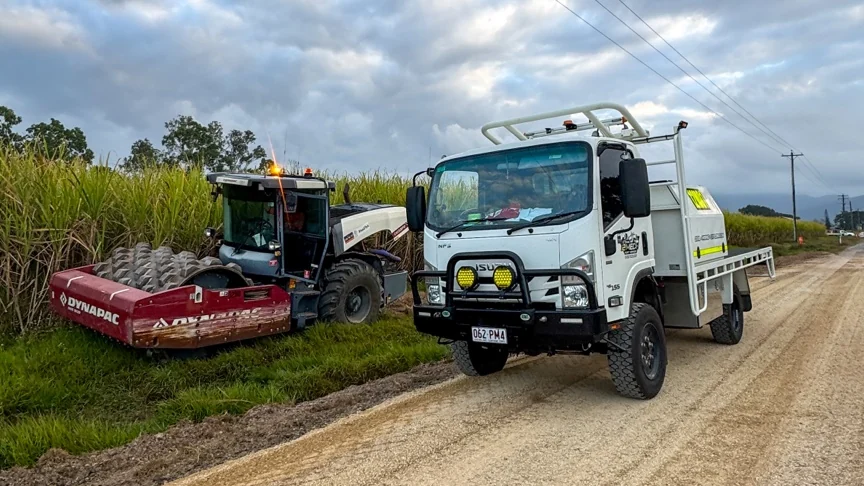 12Mech service truck parked beside a Dynapac roller on a road job next to a cane paddock