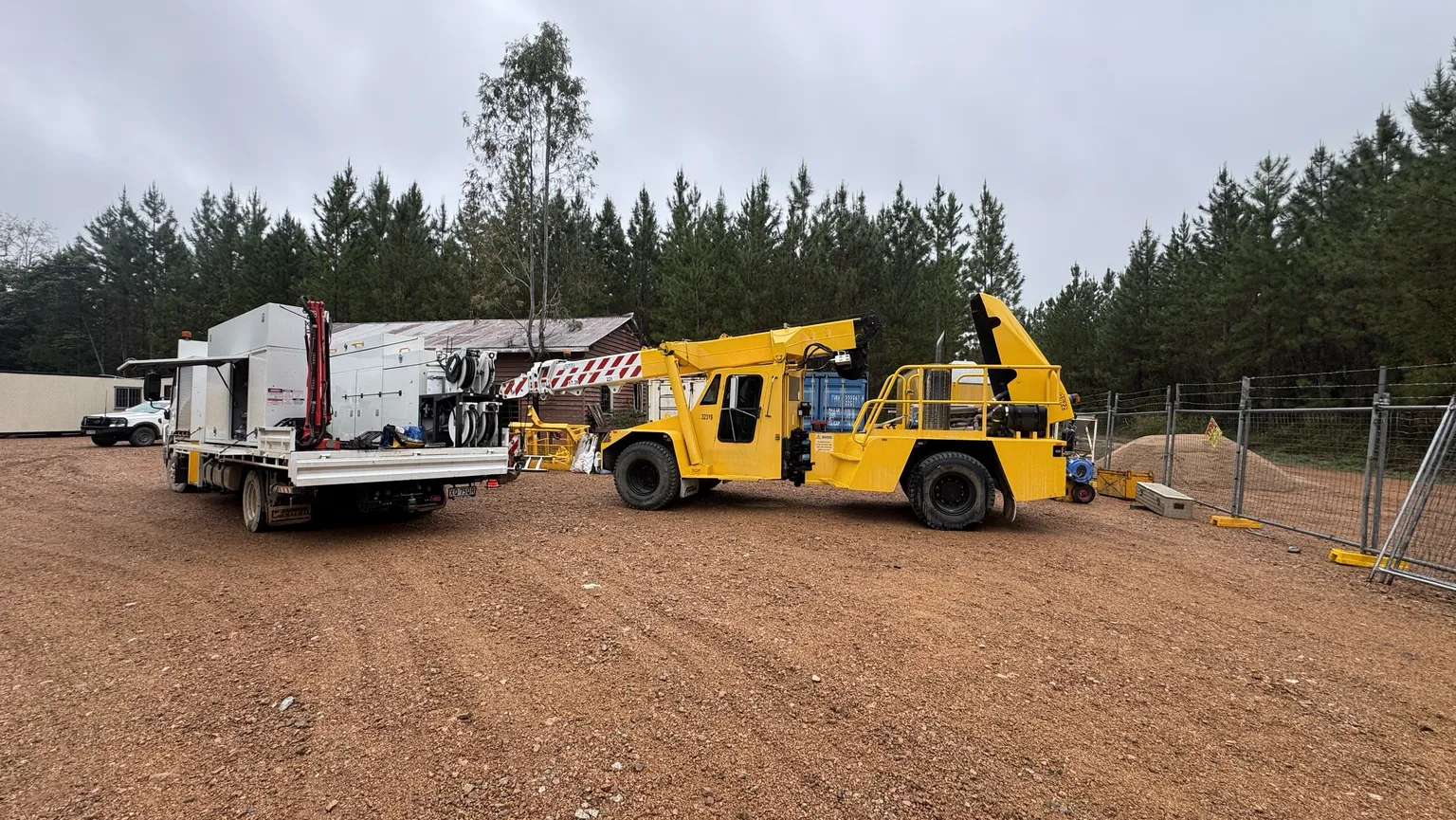 12Mech service truck with crane and hose reels beside a yellow pick-and-carry crane